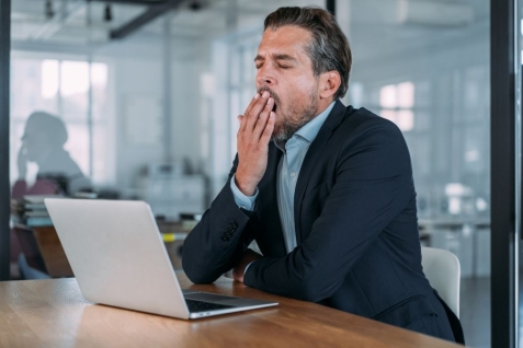 Gapende man achter laptop