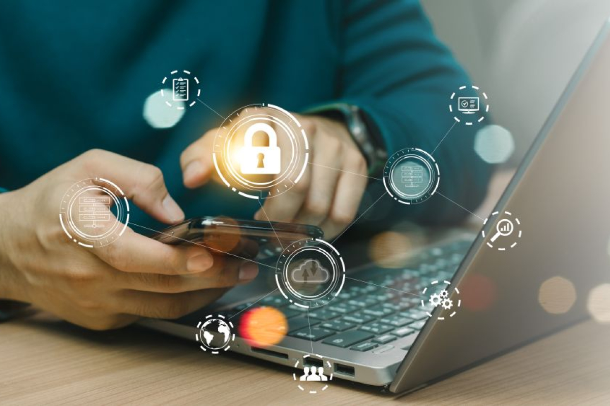 Persoon met mobiele telefoon in de hand achter laptop