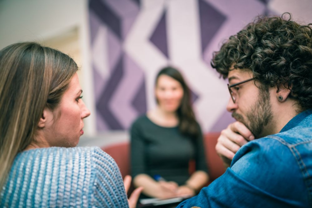Man en vrouw in gesprek met mediator in de achtergrond