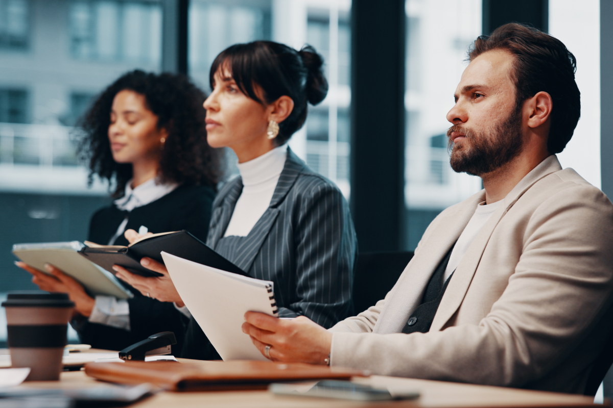 Man en twee vrouwen aan vergadertafel in kantoor tijdens training of cursus
