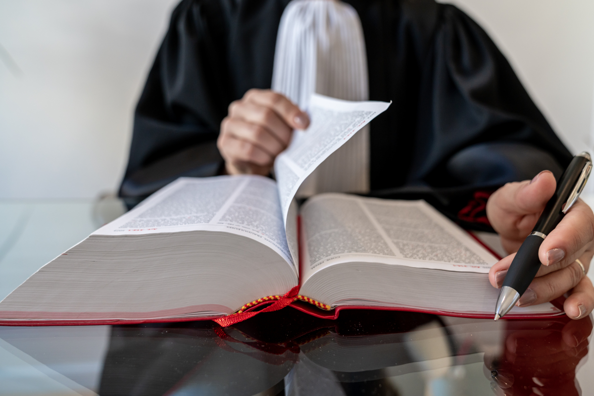 Vrouw in toga bladert door wetboek