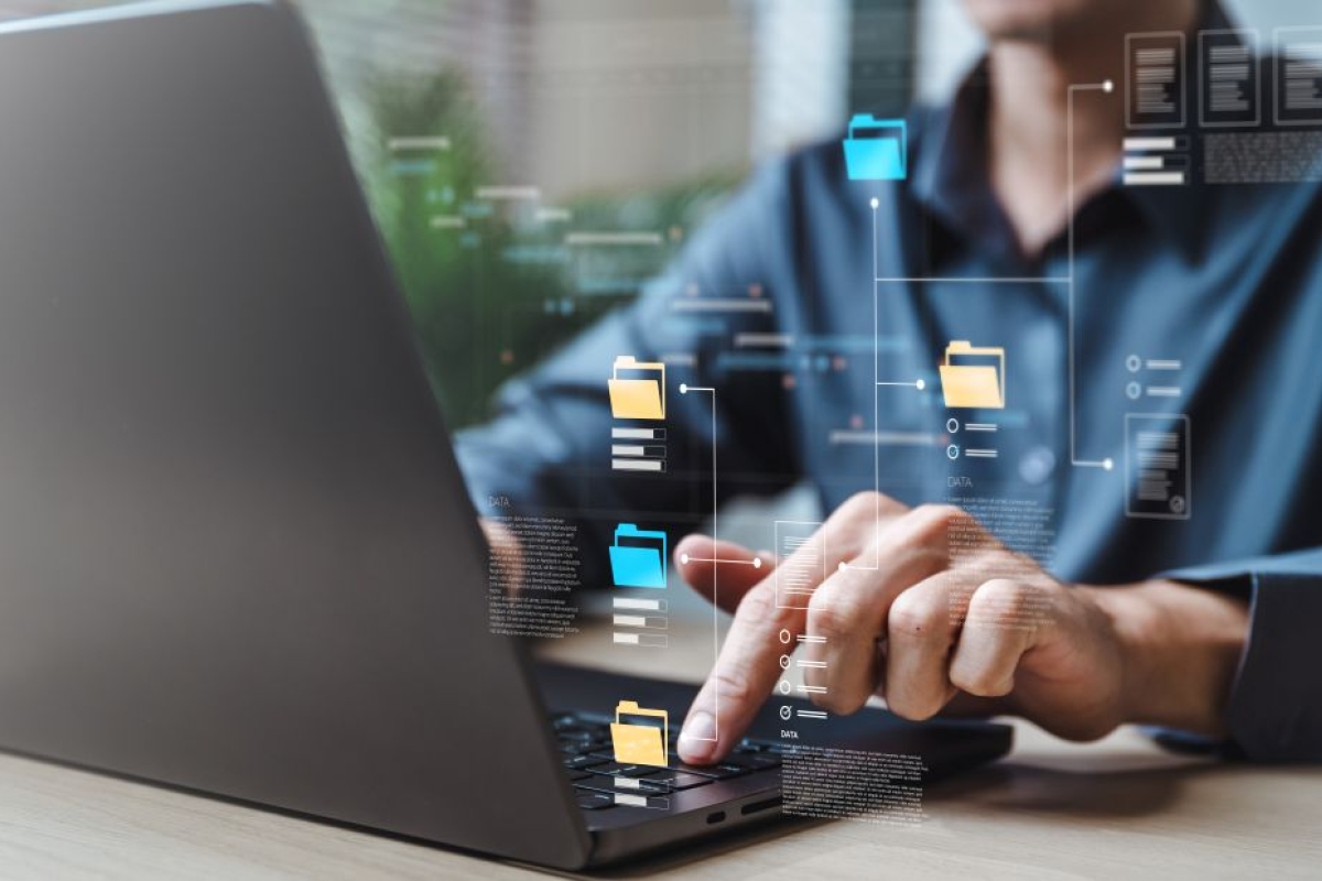 Man achter laptop met documenten in beeld