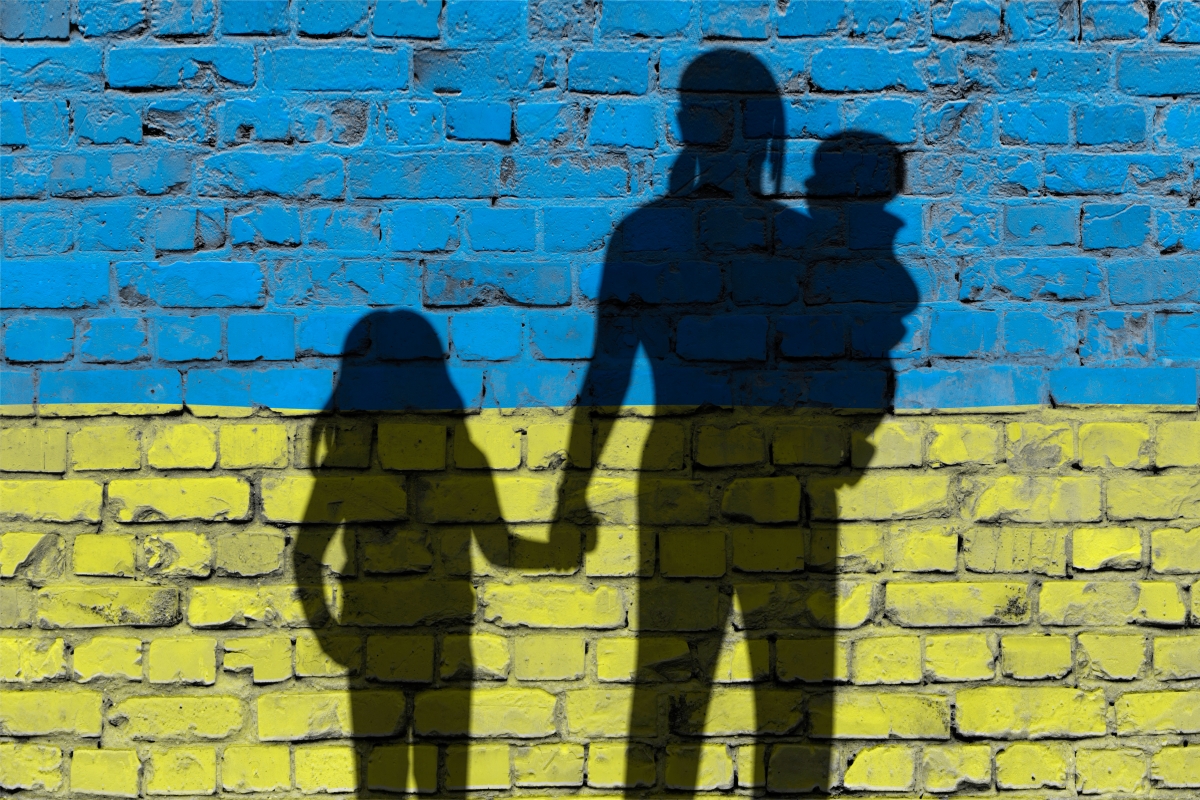 Muur in kleuren vlag Oekraine met schaduw van vluchtelingen (moeder, kinderen)