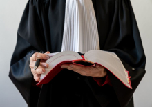 Vrouw in toga die wetboek en pen vasthoudt