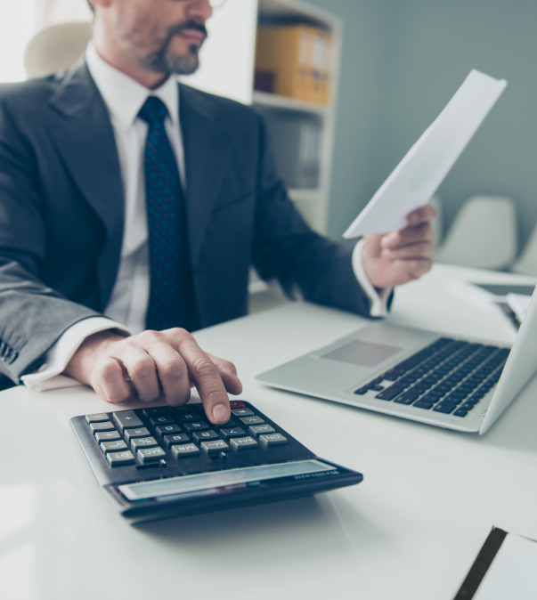 Man in pak achter laptop, A4tj in ene hand calculator bij de andere hand