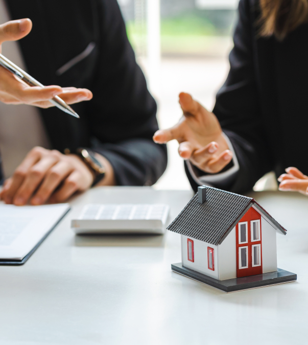 Man/vrouw in pak in discussie met op tafel calculator en huisje