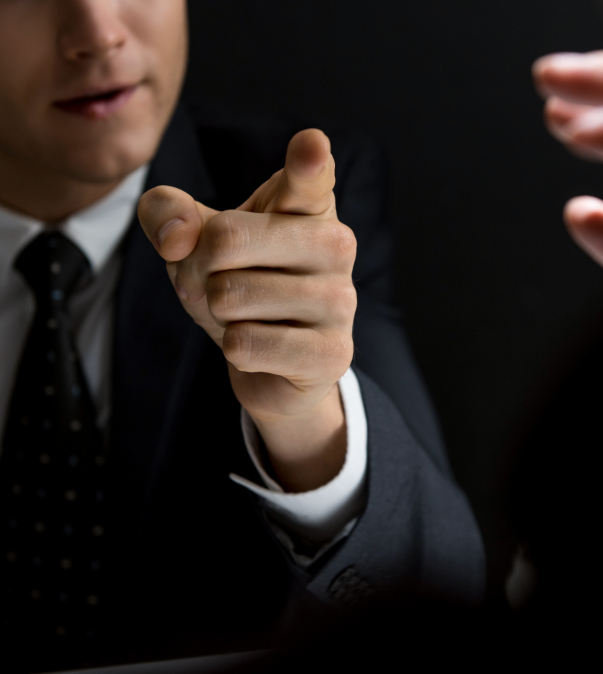 Man in pak wijst me vinger naar persoon tegenover - donkere foto