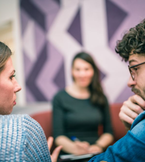 Man en vrouw in gesprek met mediator in de achtergrond