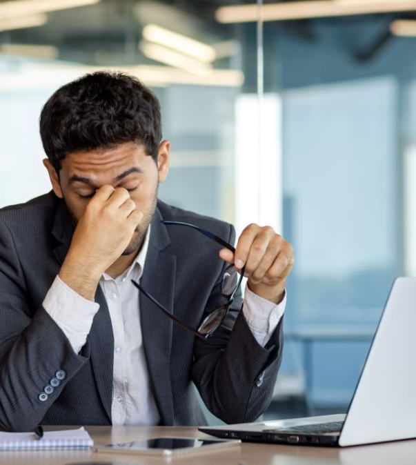 Vermoeide man op kantoor achter laptop