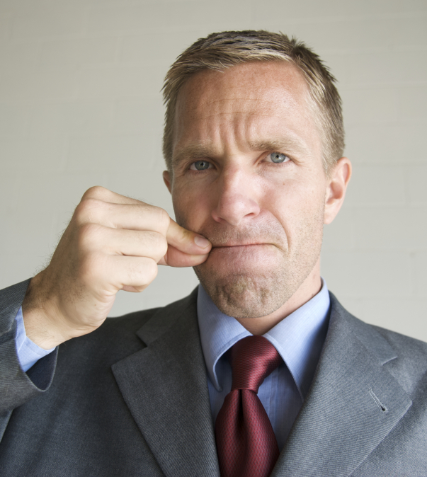 Man in pak die zijn lippen op mekaar houdt en gebaar 'ritssluiting'