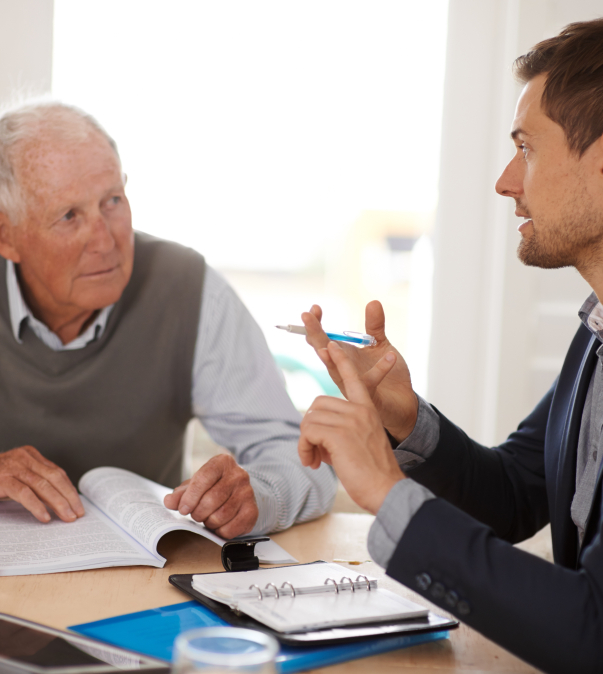 Foto jonge man die oudere man advies geeft met dossiers op tafel
